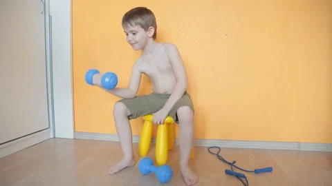 Little boy doing dumbbell exercises on biceps, triceps Stock Footage 106389013