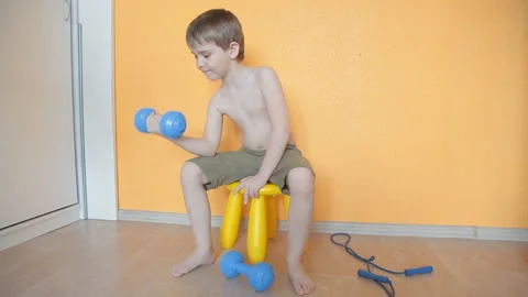 Little boy doing dumbbell exercises on biceps, triceps Stock Footage 106389364