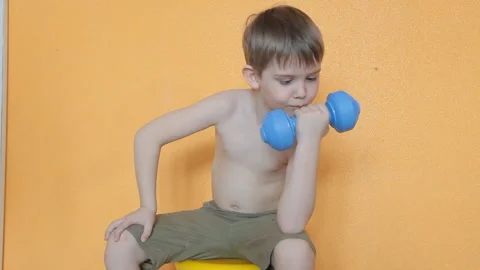 Little boy doing dumbbell exercises on biceps, triceps Stock Footage 106389827