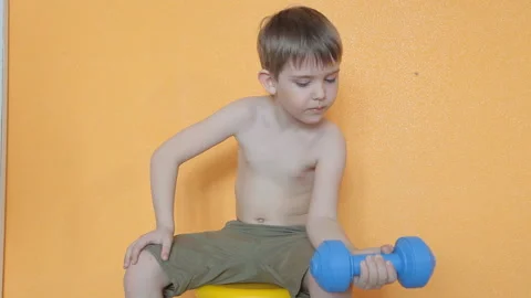 Little boy doing dumbbell exercises on biceps, triceps Stock Footage 106390594