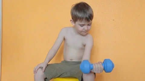 Little boy doing dumbbell exercises on biceps, triceps Stock Footage 106391130