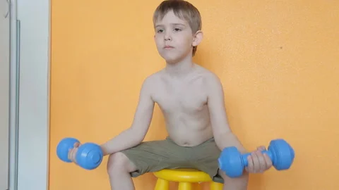 Little boy doing dumbbell exercises on biceps, triceps Stock Footage 106391546