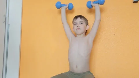 Little boy doing dumbbell exercises on biceps, triceps Stock Footage 106391802