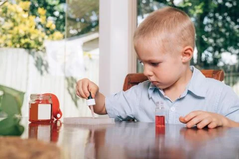 Little boy doing the experimental laboratory activity with colored water and Stock Photos