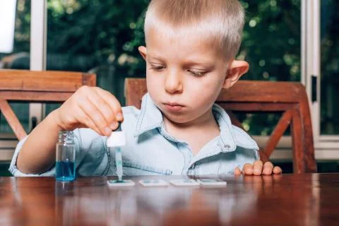 Little boy doing the experimental laboratory activity with colored water and Stock Photos
