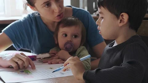 Little boy doing his math homework with a little help of his mother. The mother Video stock 182187847