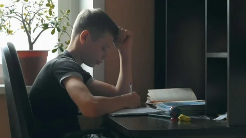 Little boy doing homework. He sits at his desk, learning to write letters Stock Footage 69865326