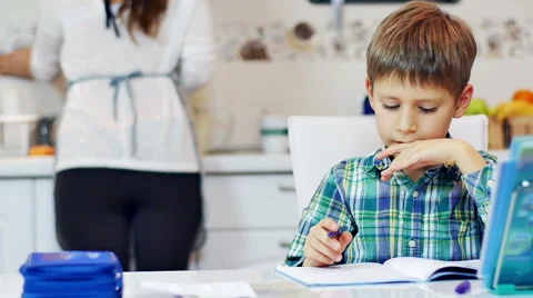 Little boy doing homework in the kitchen with his mother Stock Footage 44204143