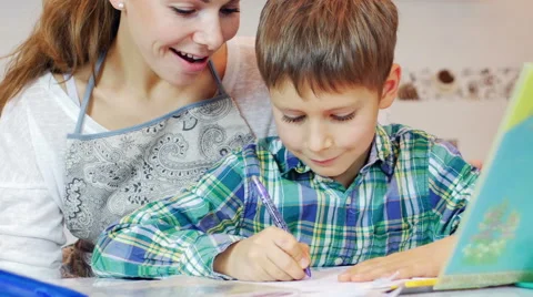 Little boy doing homework, mum checking on him Stock Footage 44192429
