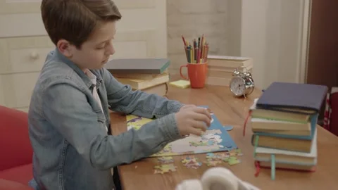 A little boy is doing a jigsaw puzzle at his desk. Video stock 198334237