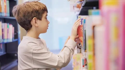 Little boy doing research in a library. Young child looking for a book Stock-Footage 242528427