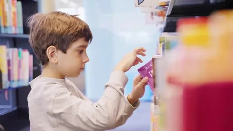 Little boy doing research in a library. Young child looking for a book Stock Footage 242528444