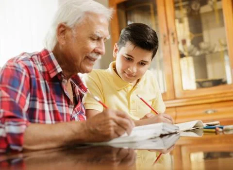 Little Boy Doing School Homework With Old Man At Home Stock Photos