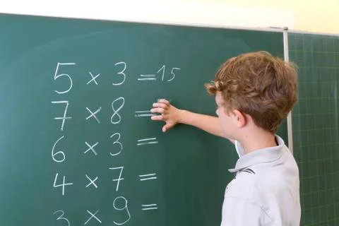 Little boy is doing some maths at a blackboard 库存照片