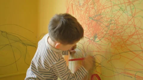 Little boy drawing on the yellow wall at home Stock Footage 89904142