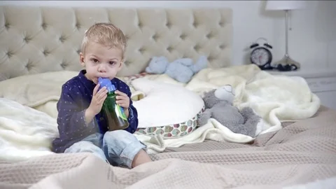 Little boy is drinking on a bed. FULL HD. tracking shot Stock Footage 73966189