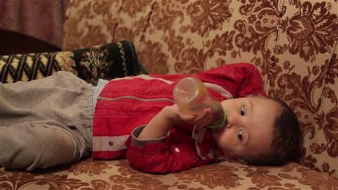 Little boy drinking from a bottle lying down Video stock 82897410