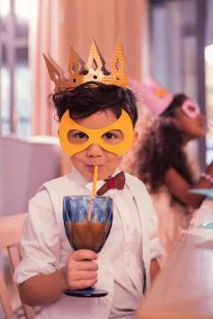 Little boy drinking juice with sipping straw while being at masquerade Stock Photos