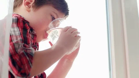 Little boy drinking water from glass, thirsty kid, closeup portrait, water for Stock Footage