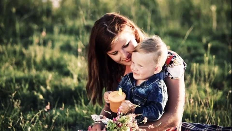 Little boy drinks a drink sitting at mom on hands Stock Footage 76927064