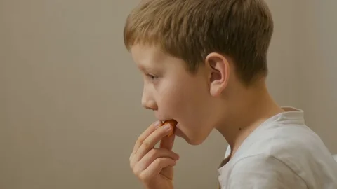 A little boy eating carrot on the grey background Stock Footage