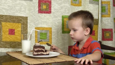 Little boy eats cake using a spoon. A happy child loves sweetness. Stock Footage 136112934