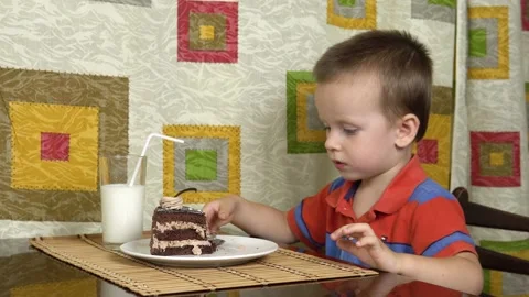 Little boy eats cake using a spoon. A happy child loves sweetness. Stock Footage 136386374