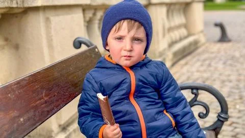 A little boy eats a chocolate ice cream candy on a stick. Close-up of a his face Stock-Fotos