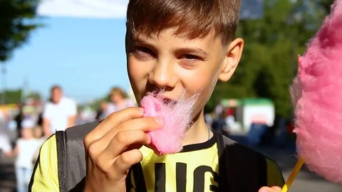 Little boy eats cotton candy at an amusement park. Video stock 117939720