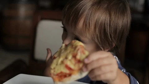 Little boy eats pizza and licks his fingers Stock Footage 122506205