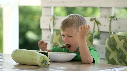 A little boy eats winter soup at a table in a gazebo in the garden and watche Stock Footage 138243197