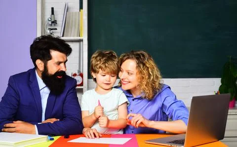 Little boy from elementary school doing schoolwork with teachers man and woma Stock Photos