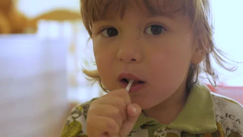 Little boy enjoying a lollipop while staring at camera. Child eating candy, s Stock Footage 90502885