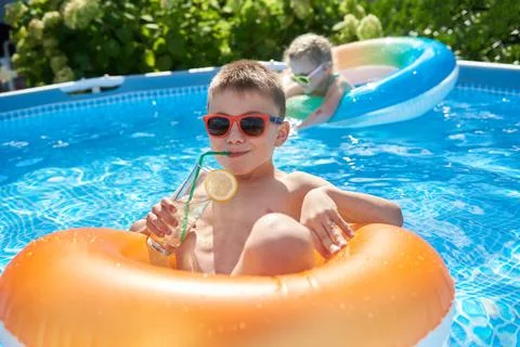 Little boy enjoying summer in the pool and drinking a cocktail Stock Photos