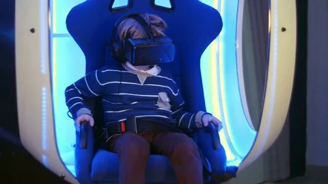 Little boy experiencing virtual reality sitting in interactive moving chair Stock Footage 76856982