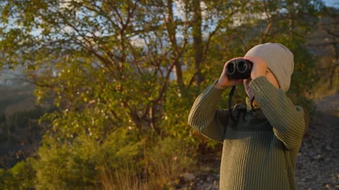 Little boy explores horizon with binoculars during golden hour hike Stock Footage 305508316