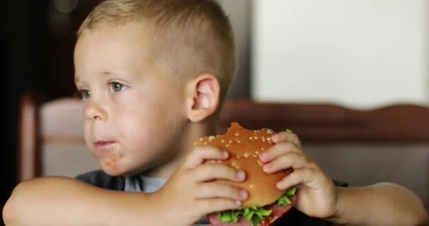 Little boy in fast food cafe eats burger. little kid eating burger. Stock Footage 202547341