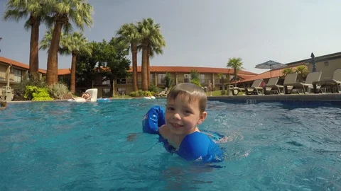 Little boy with floaties in pool looks at camera Stock Footage 94227983