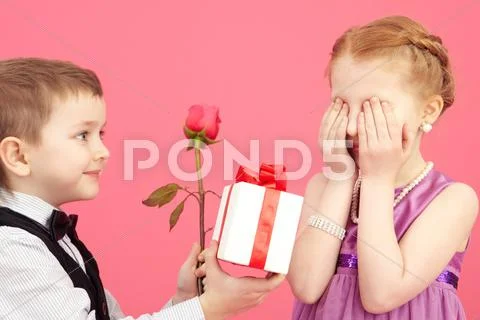 Little boy giving a rose and gift box to his girlfriend Stock Photos