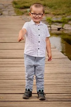 Little boy in glasses posing in nice dress for portrait in summer park Stock Photos