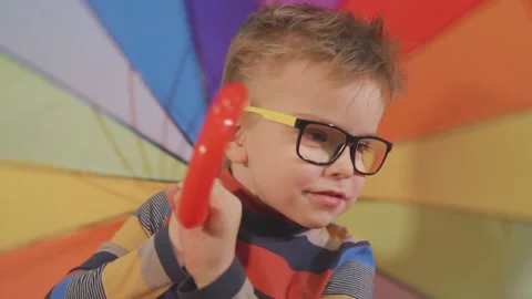 Little boy with glasses twists a multi-colored umbrella Stock Footage 142858749