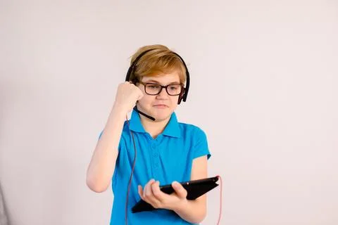 Little boy in glasses using a tablet computer with a light background Stock Photos
