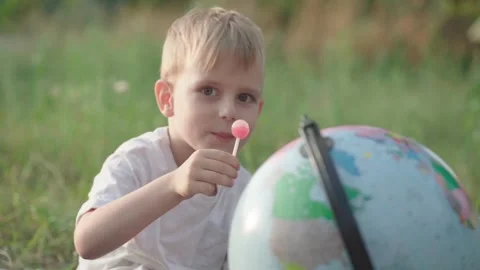 A little boy with a globe is looking and smiling at the camera. Slow motion Stock Footage 248494227