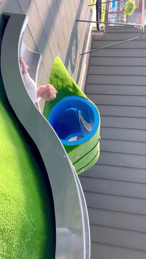 A little boy goes down a slide and runs after a ball. Stock Footage 310316372