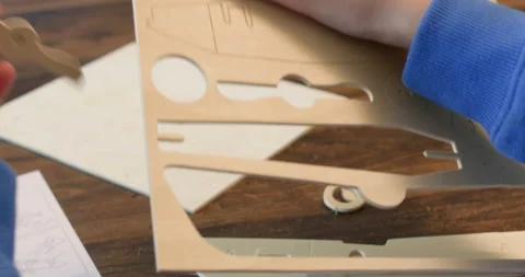 Little boy hands take propeller of airplane model out of plywood Stock Footage 323971759