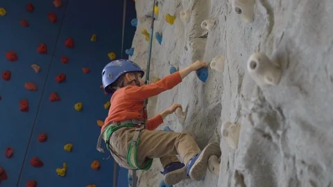 Little boy in a harness climbing a wall with grips Stock Footage 106840184
