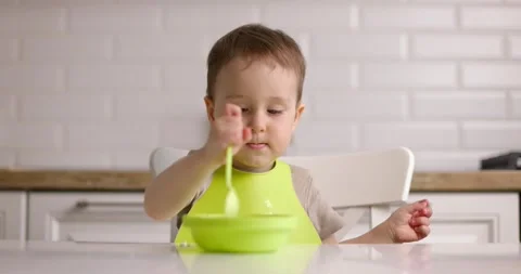 Little boy has breakfast in the kitchen. Happy baby eats porridge with spoon Video stock 154872608