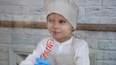 A little boy in a hat and apron makes himself a lollipop made of soft caramel. Stock-Footage 328024595