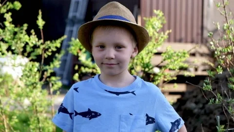 Little boy in a hat looking at camera and smiling, countyside Stock Footage 89517378