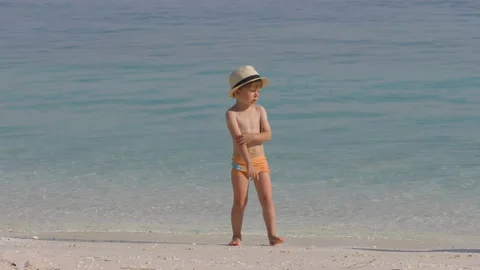 Little boy with hat standing on beach watching the sea Stock Footage 219332754